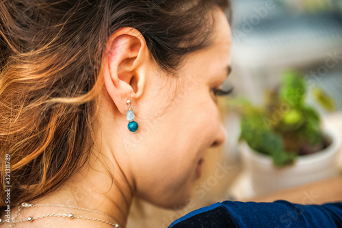 Woman and earrings made of natural stones. The mysticism of amulets. Esoterics in handmade jewelry close-up and copy space. Jewelry on the female neck.