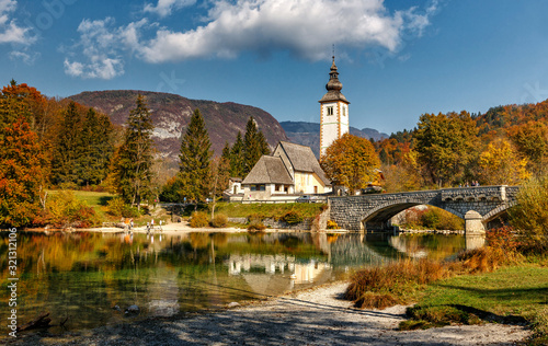 Amazing nature landscape. Bohinj Lake, Church of St John the Baptist with bridge. Triglav National Park, Julian Alps, Slovenia. Colorful summer panorama. Wonderful sunny scenery