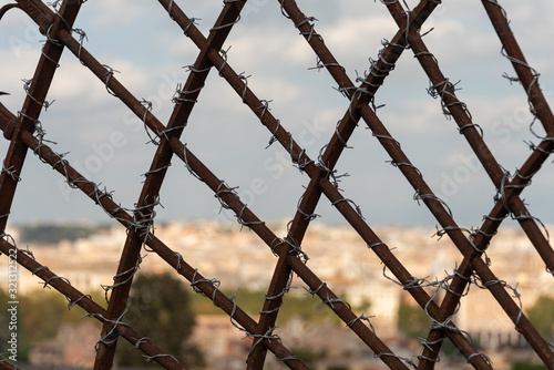 Steel fence covered with barbed wire, Blurred cityscape in the background. 