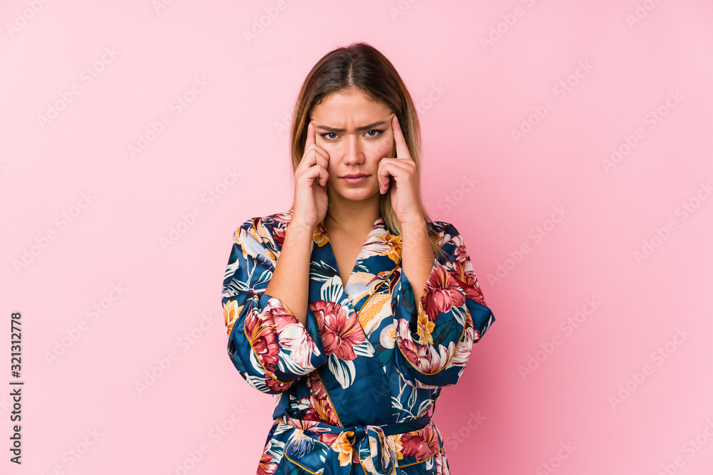Young caucasian woman wearing pajamas focused on a task, keeping forefingers pointing head. Young caucasian woman wearing pajamas focused on a task, keeping forefingers pointing head.