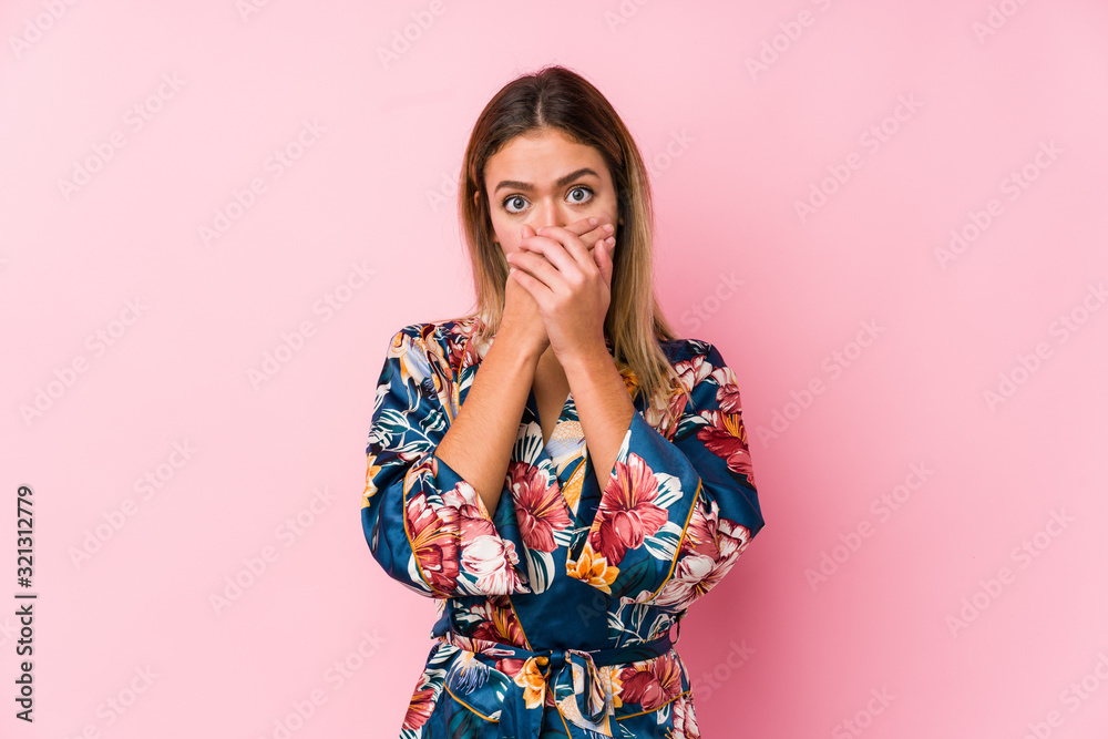 Young caucasian woman wearing pajamas shocked covering mouth with hands. Young caucasian woman wearing pajamas shocked covering mouth with hands.