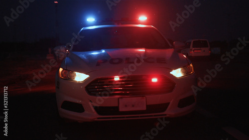 View of police car on emergency call driving fast to the accident area at night. Policemen speeding to the scene of crime. City safety and security.