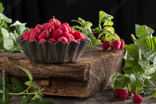 Raspberry. Fresh juicy berries from the garden in an iron pot on a wooden table. Raspberry With green leaves. Fresh organic berries macro View from above. Top view. Close-up photo.