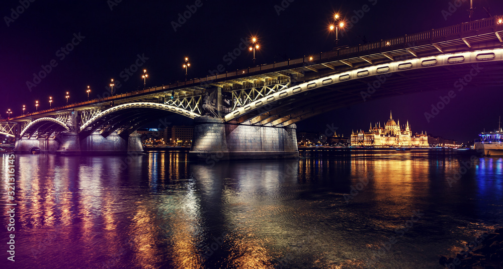 Wonderful evening cityscape. Parliament and Margaret bridge illuminated, in Budapest at night reflected in the calm water Danube river, Hungary