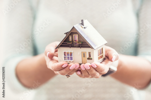 Hands of young woman holding model house