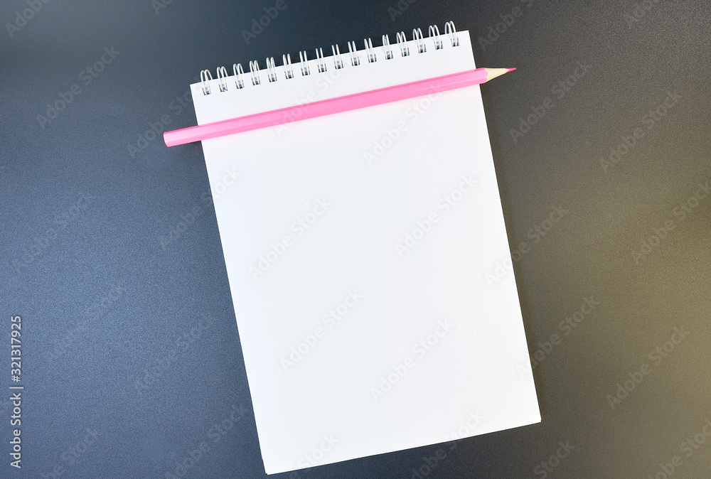 Pink pencil on a white sheet of notepad paper on a dark gradient from brown to blue background. Blank paper sheet and pencil for mock up. copy space. flat lay Pink pencil on a white sheet of notepad paper on a dark gradient from brown to blue background. Blank paper sheet and pencil for mock up. copy space. flat lay