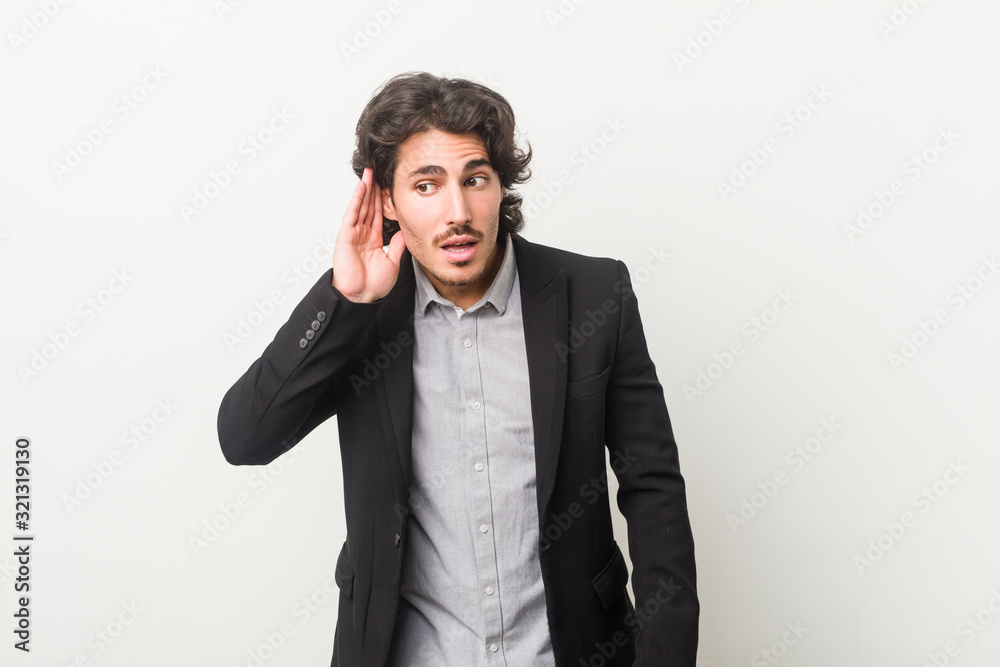 Young business man against a white background trying to listening a gossip. Young business man against a white background trying to listening a gossip.