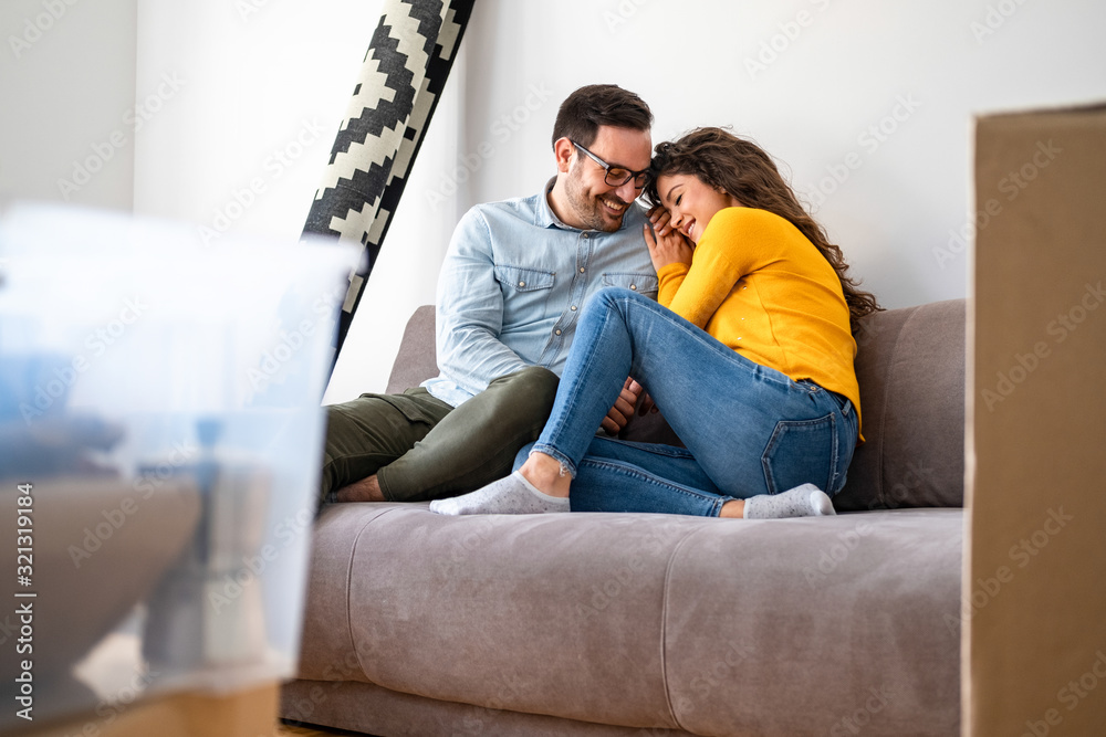 Happy couple cuddle in couch and celebrating moving to new home Happy couple cuddle in couch and celebrating moving to new home
