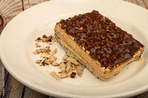 A piece of waffle cake on a white plate on a wooden background. Close up.