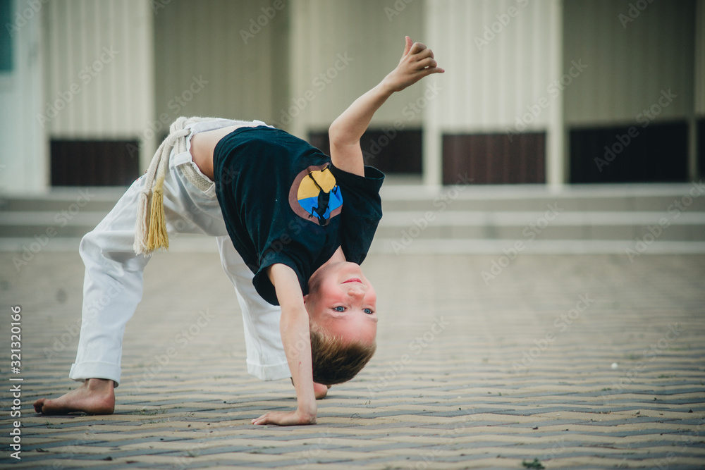 the boy is engaged in capoeira on the street