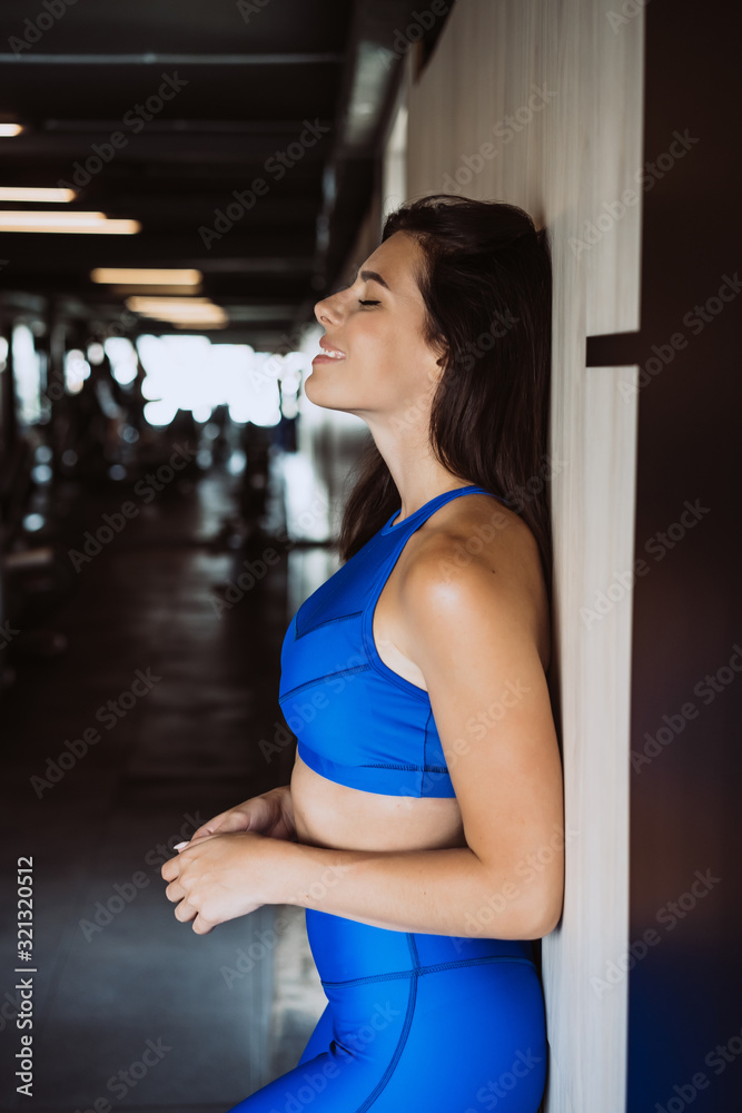 Image of happy sports young girl standing and posing over black wall. Female resting after fitness.