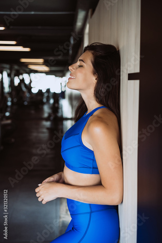 Image of happy sports young girl standing and posing over black wall. Female resting after fitness.