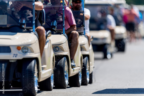 Row of Golf Carts Driving on a Golf Course Cart Path