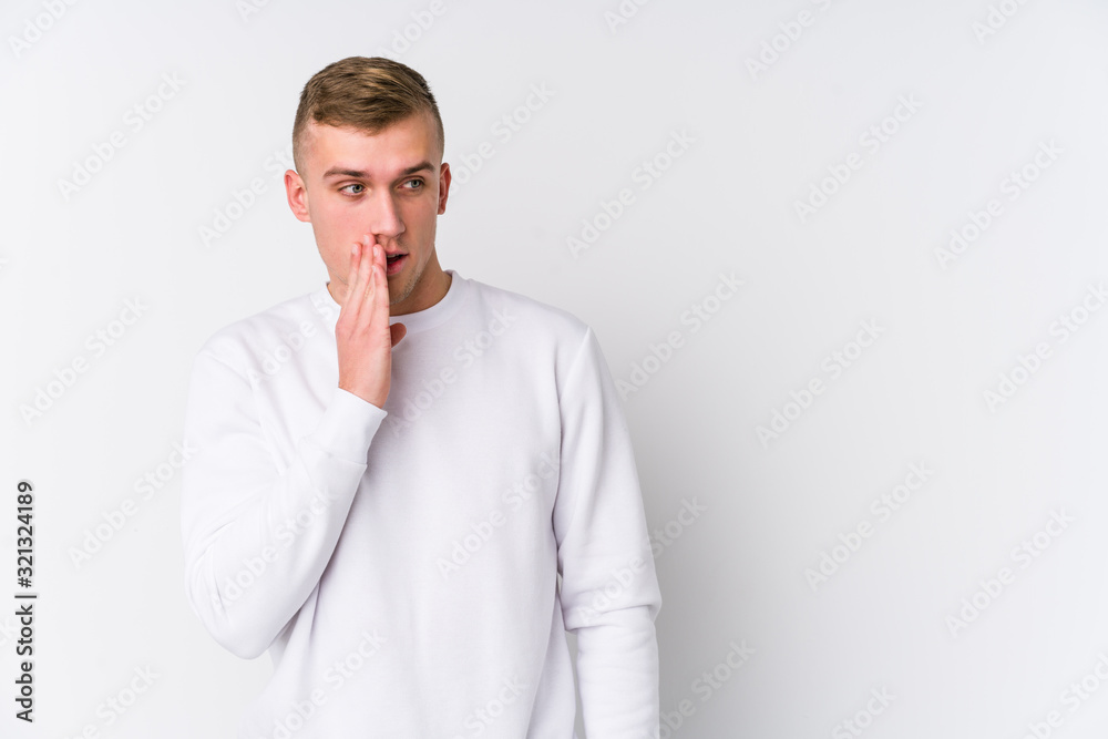 Young caucasian man on white background is saying a secret hot braking news and looking aside Young caucasian man on white background is saying a secret hot braking news and looking aside