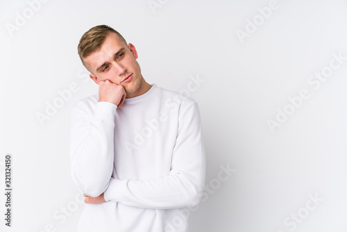 Young caucasian man on white background who feels sad and pensive, looking at copy space.