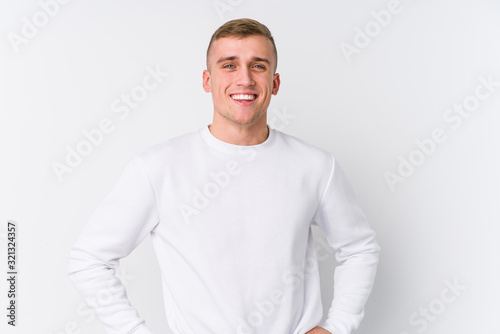 Young caucasian man on white background confident keeping hands on hips.