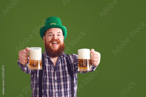 Happy St. Patrick's Day. Fat man in a green hat holds his hands up glasses with beer photo