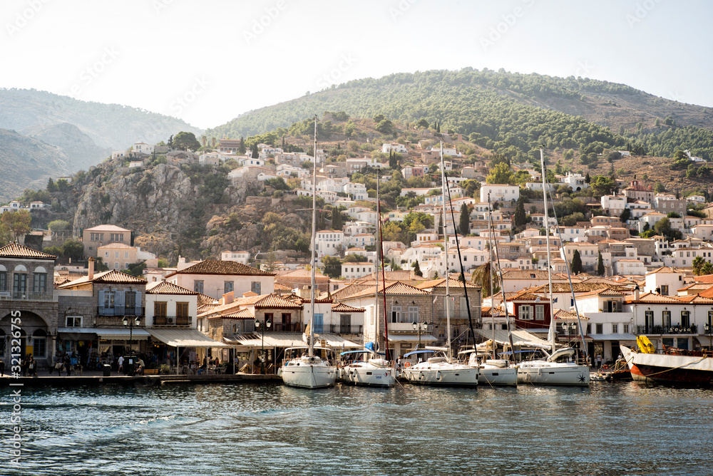 Fototapeta premium View of Hydra, Greece seaside town with hills, building and sailboats