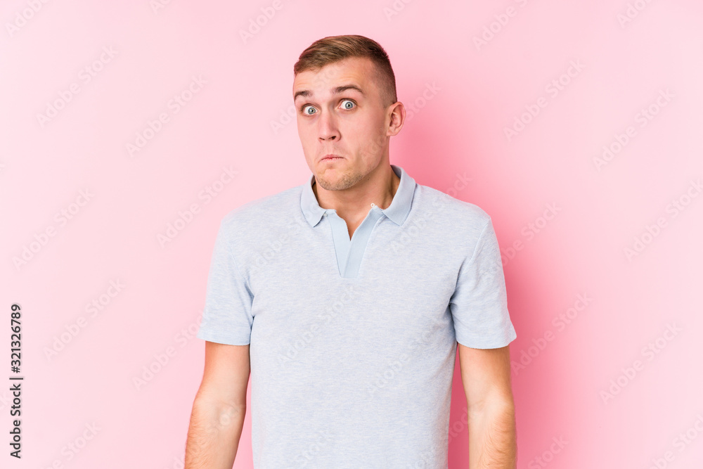 Fototapeta premium Young caucasian man isolated shrugs shoulders and open eyes confused.