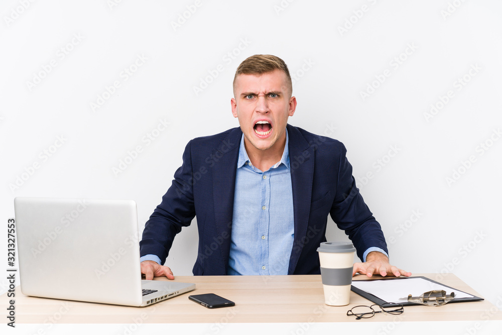 Young business man with a laptop screaming very angry and aggressive. Young business man with a laptop screaming very angry and aggressive.