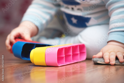 Little boy is playing with toys on the floor.