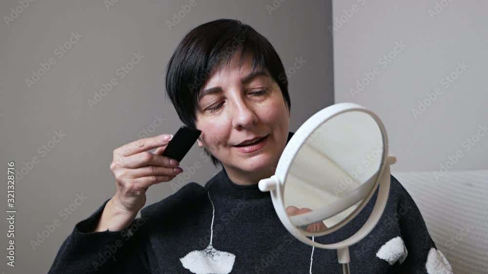 Attractive elderly woman combing her hair in front of a mirror and smiling, aged beauty Attractive elderly woman combing her hair in front of a mirror and smiling, aged beauty