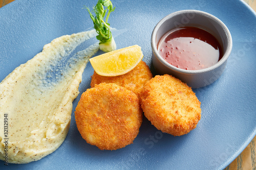 Photos Appetizing breadcrumb shrimp croquettes with red sauce on a blue plate