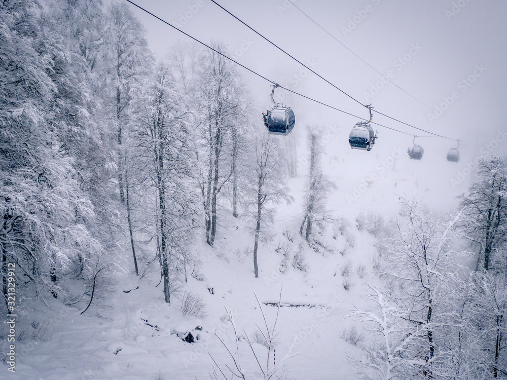 Winter Mountain landscape at the Rosa Khutor ski resort in Sochi, Russia. Cable car cabin over pine trees in the snow Winter Mountain landscape at the Rosa Khutor ski resort in Sochi, Russia. Cable car cabin over pine trees in the snow