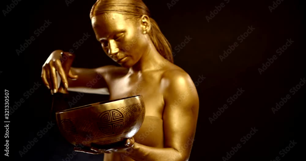 young golden woman is striking by tibetan bronze bowl and enjoying healing sound young golden woman is striking by tibetan bronze bowl and enjoying healing sound