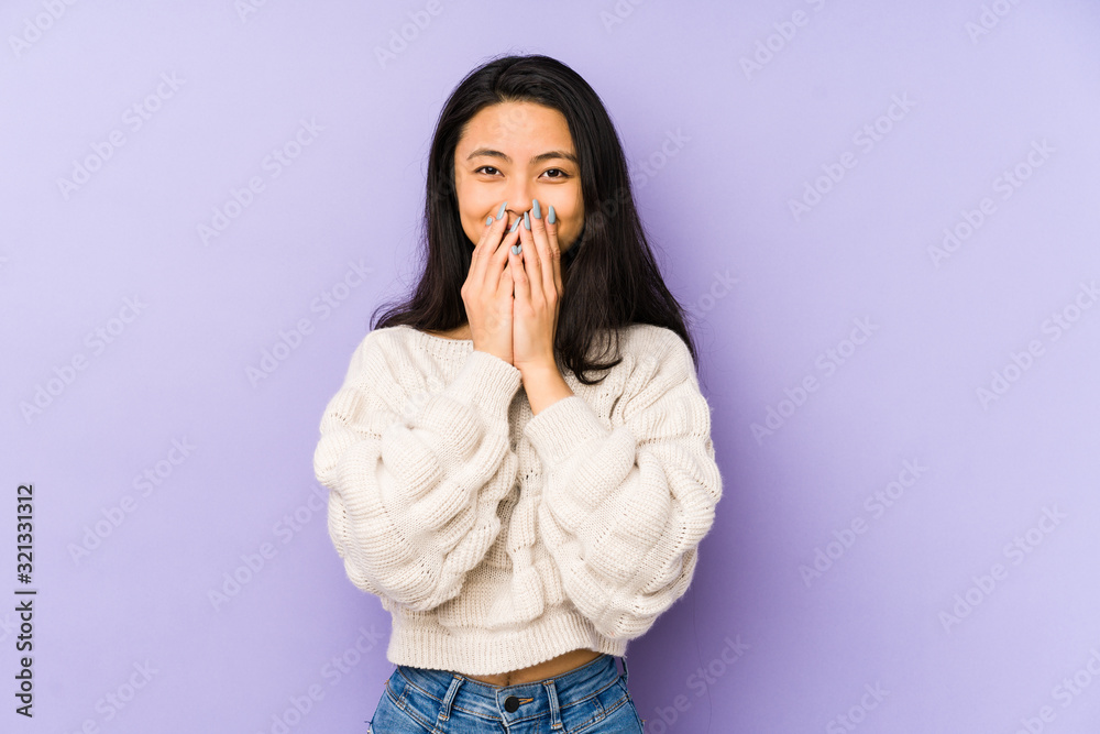 Young chinese woman isolated on a purple background laughing about something, covering mouth with hands. Young chinese woman isolated on a purple background laughing about something, covering mouth with hands.