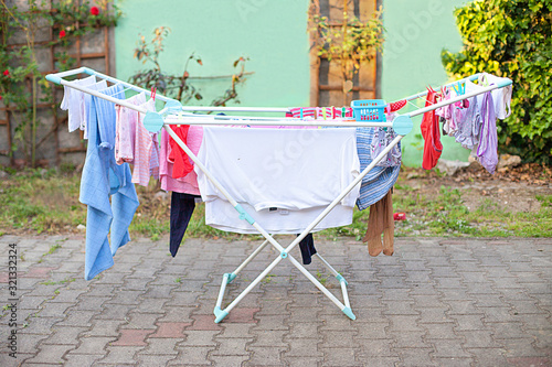 Clotheshorse on cortis. Drying rack with loundry on the garth. Rack dryer with clothes on backyard, sunny day. Clothes rack on the courtyard. Drying horse with airing loundry. Clothes maiden outdoors. photo