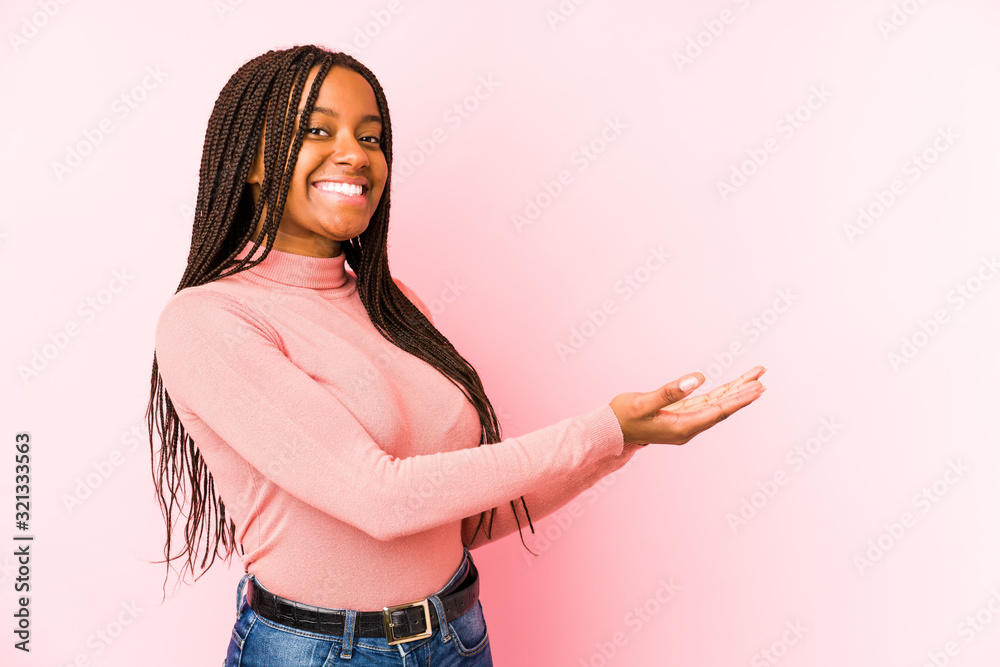 Young african american woman isolated on a pink background holding a copy space on a palm. Young african american woman isolated on a pink background holding a copy space on a palm.