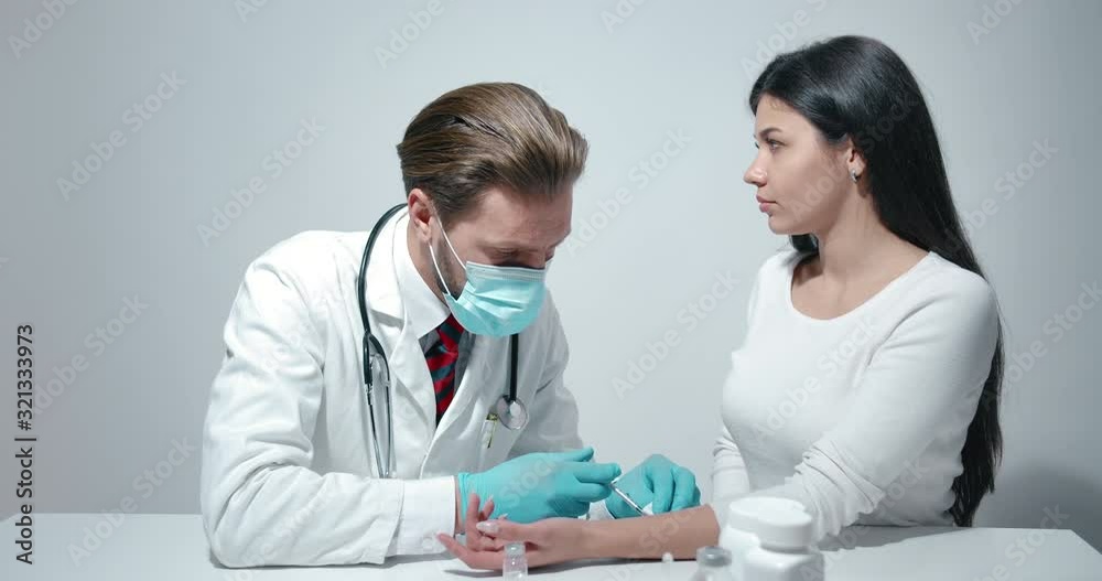 Male doctor in protective mask making injection to young female patient, vaccination Male doctor in protective mask making injection to young female patient, vaccination