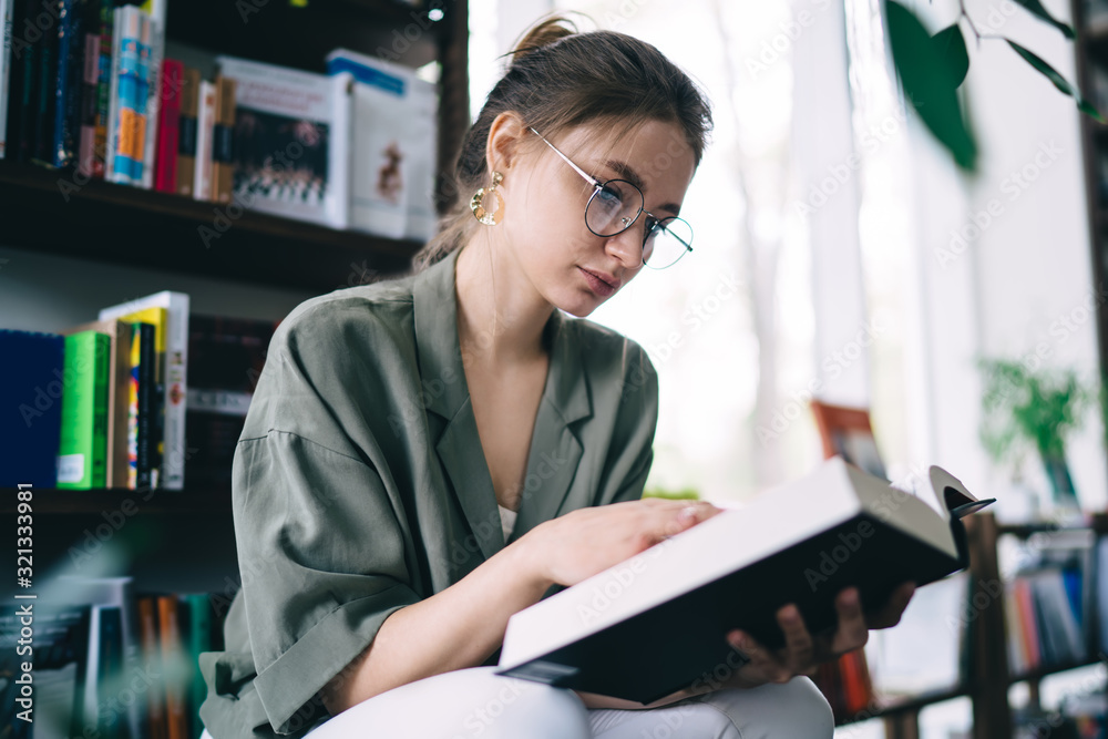 Calm woman reading story while sitting in library Calm woman reading story while sitting in library