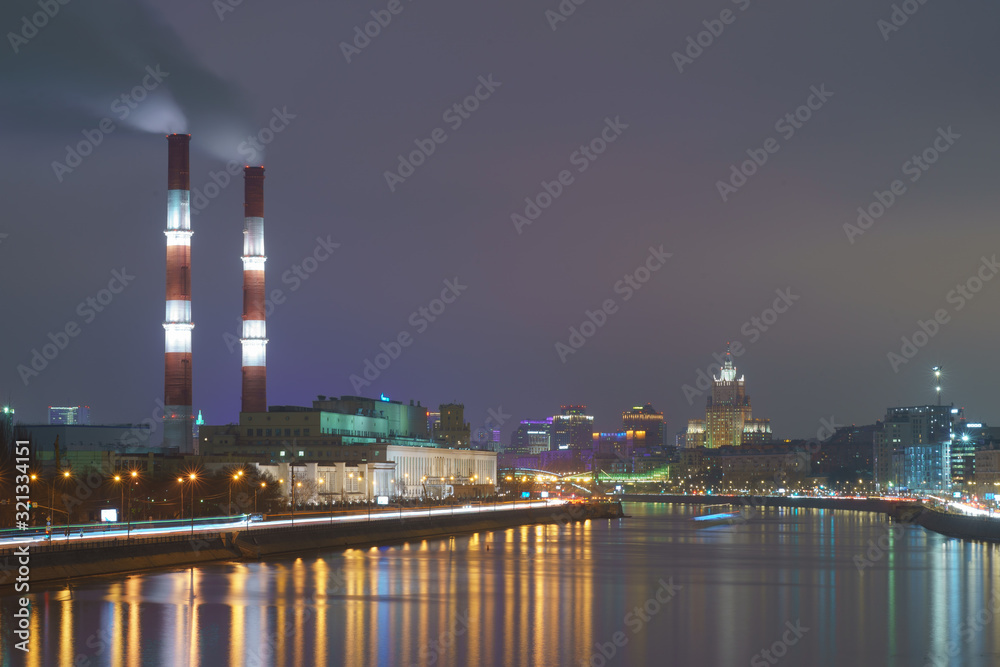 Fototapeta premium Smoking pipes on sky background in winter. Cimneys, concept of industry and ecology, heating season, modern global warming, air pollution. Heat station pipes. High angle view.