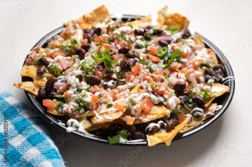 Mexican nachos with beans and pico de gallo sauce on white background