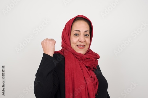 Overjoyed happy excited muslim female glad to receive good news, gestures actively from happiness, clenching fist and making winning gesture. Reaction concept.