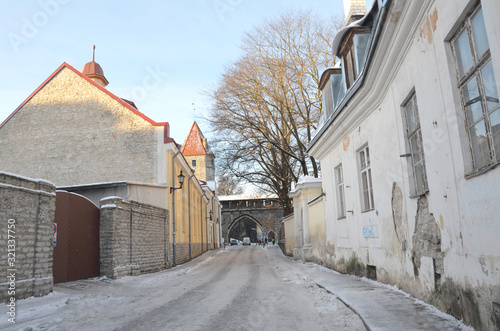 Beautiful street of Old Tallinn. Tourists walk down a picturesque snowy street in a residential and business area of the medieval old town in Tallinn.