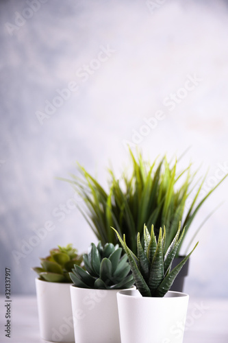 Artificial flowers grass different form in a pot on wooden background close up with copy space and text