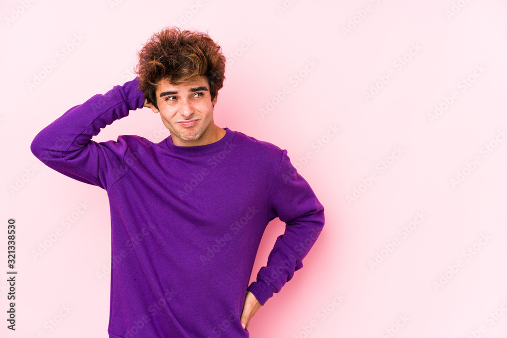 Young caucasian man against a pink background isolated touching back of head, thinking and making a choice. Young caucasian man against a pink background isolated touching back of head, thinking and making a choice.