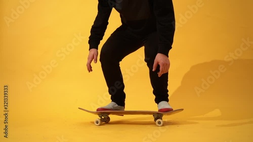Skateboarder performing skateboard trick - ollie in the studio. Stunt shot of athlete practicing jump on yellow background, preparing for competition. Extreme sport, youth culture