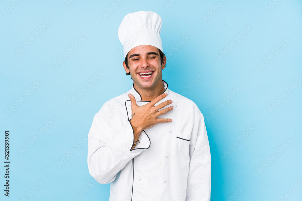 Young cook man isolated laughs out loudly keeping hand on chest.