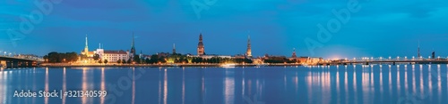 Riga, Latvia. Panoramic Picturesque Urban View Of Daugava Or Western Dvina River In Central Part Of City With Famous Landmarks In Bright Illumination Under Blue Sky In Summer Night © Grigory Bruev