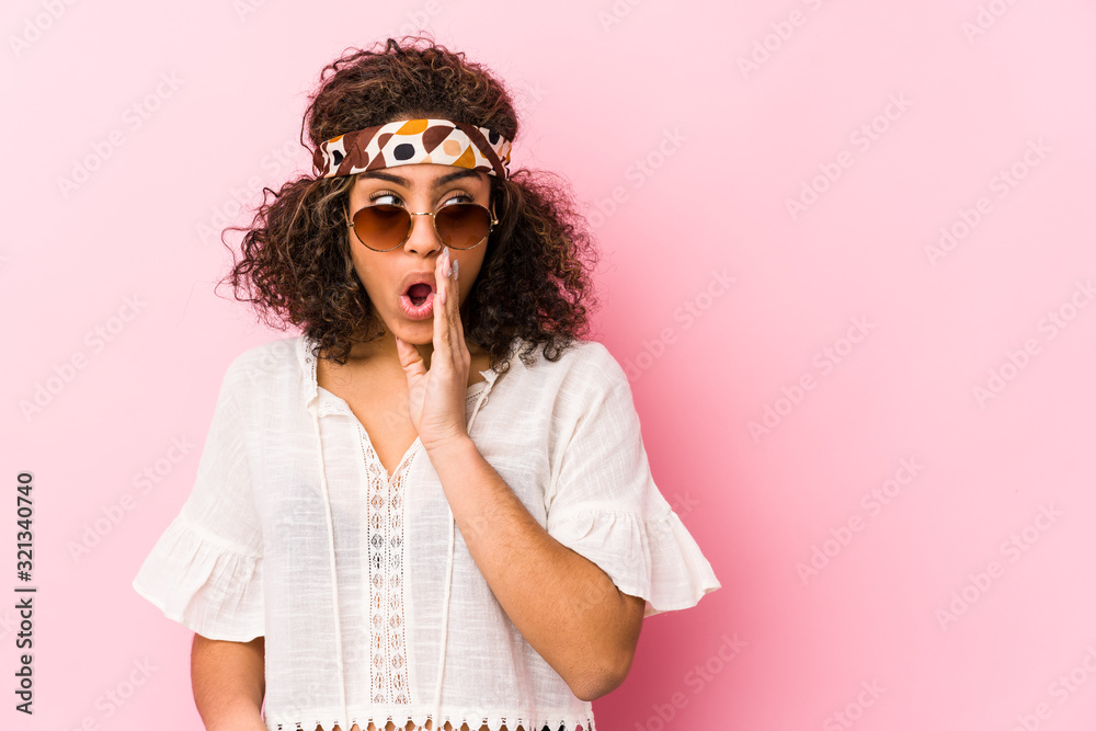 Young african american hipster woman isolated on pink background is saying a secret hot braking news and looking aside