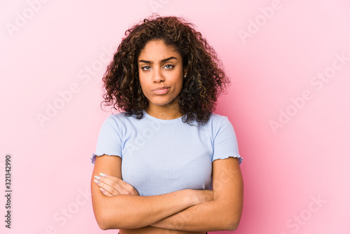 Photography Young african american woman against a pink background frowning face in displeasure, keeps arms folded