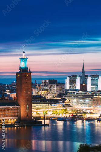 Stockholm, Sweden. Scenic Skyline View Of Famous Tower Of Stockholm City Hall And St. Clara Or Saint Klara Church. Popular Destination Scenic View In Sunset Twilight Dusk Lights. Evening Lighting