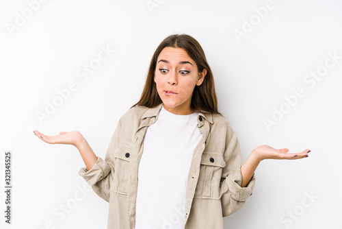 Young caucasian woman  isolated confused and doubtful shrugging shoulders to hold a copy space.