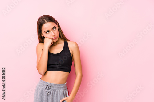 Young caucasian fitness woman posing in a pink background who feels sad and pensive  looking at copy space.