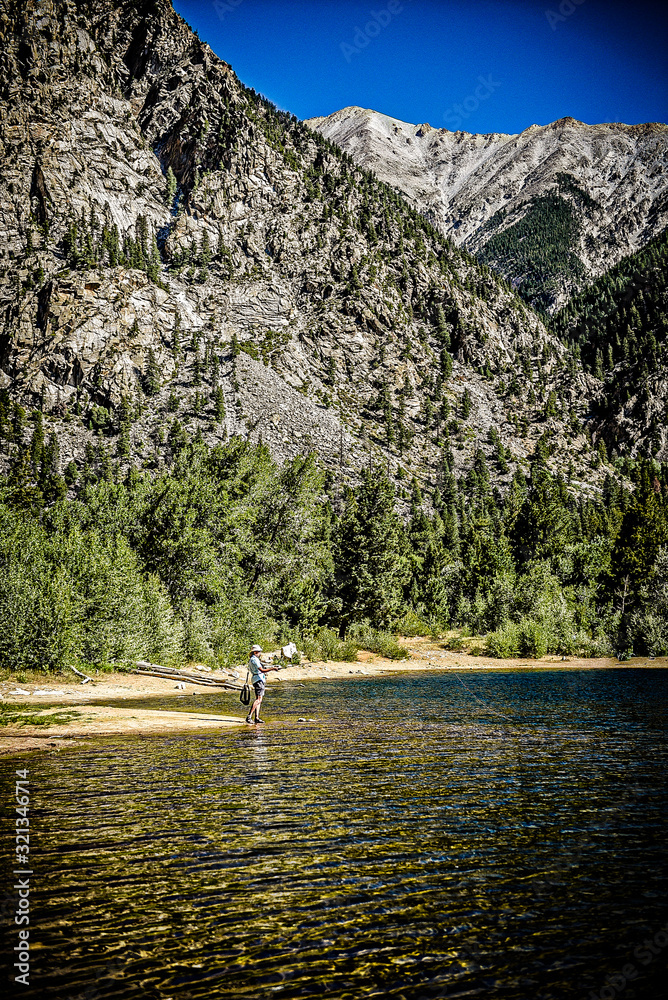 Fototapeta premium Woman fly fishing in alpine lake