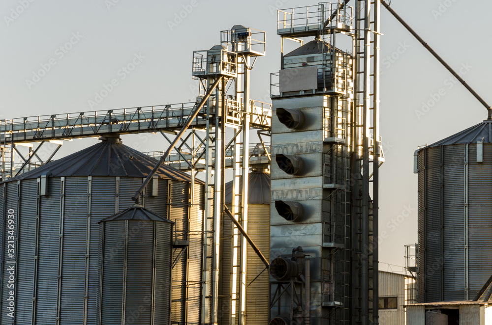 A large modern plant for the storage and processing of grain crops. view of the granary on a sunny day against the blue sky. End of harvest season. A large modern plant for the storage and processing of grain crops. view of the granary on a sunny day against the blue sky. End of harvest season.